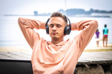 Kulaklıklı ve laptoplu rahat bir genç adam.