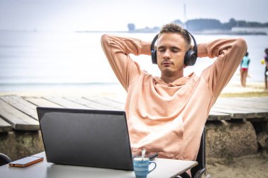 Kulaklıklı ve laptoplu rahat bir genç adam.