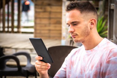 Açık kafede dijital tabletli ya da kitaplı bir adam