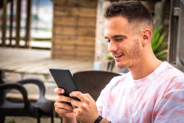 Açık kafede dijital tabletli ya da kitaplı bir adam