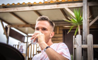 Genç adam terasta kahve içiyor.