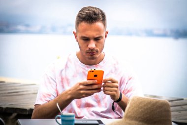 Genç adam dışarıda cep telefonu kullanıyor.