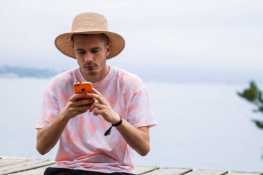 Genç adam dışarıda akıllı telefon kullanıyor.