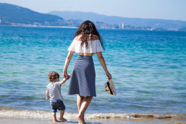 Anne ve çocuk sahilde yürüyor.