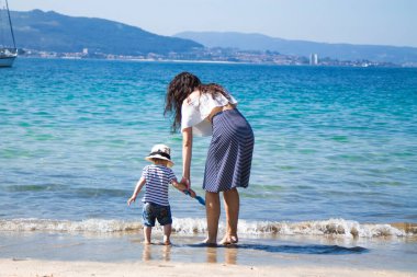 Anne ve çocuk sahilde yürüyor.