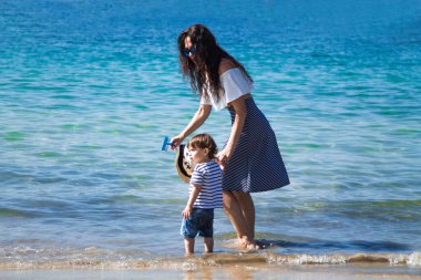 Anne ve çocuk sahilde yürüyor.