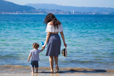 Anne ve çocuk sahilde yürüyor.