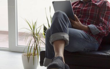 Adam dijital tablet ya da e-kitap kullanarak oturuyor