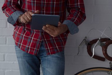 Adam dijital tablet kullanıyor. Kopya alanı olan klasik bisikletin yanında.