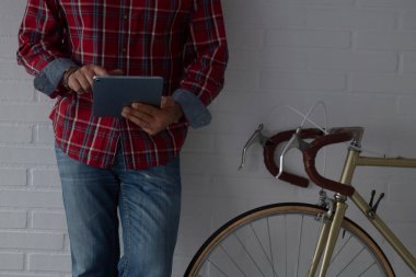 Adam dijital tablet kullanıyor. Kopya alanı olan klasik bisikletin yanında.