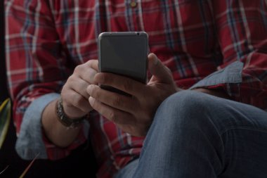 Koltukta rahat bir adam ve cep telefonu.