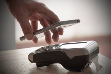POS 'a ödeme yapan cep telefonlu bir el.