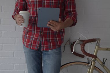 dijital tabletli hippi adam ve bisikletin yanında kahve.