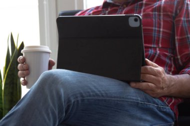 Dijital tabletli ve kanepede oturan hippi adam.