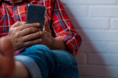 Rahat adam koltukta fotokopi alanı olan cep telefonu kullanıyor.