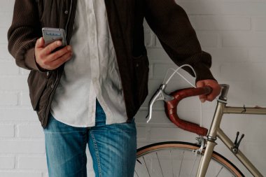 Duvarında cep telefonu ve bisikleti olan bir adam.