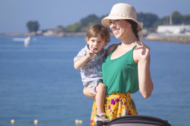 Anne ve küçük çocuğu ve bebek arabası yolda.