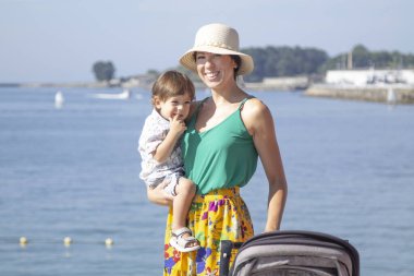 Anne ve küçük çocuğu ve bebek arabası yolda.