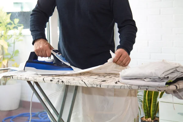 İnsan evde demirle ütü yapıyor, ev işlerinde eşitlik kavramı.