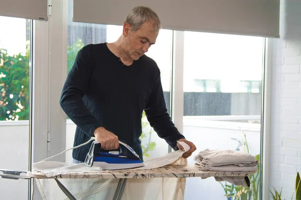 Evde ütüleyen olgun bir adam.