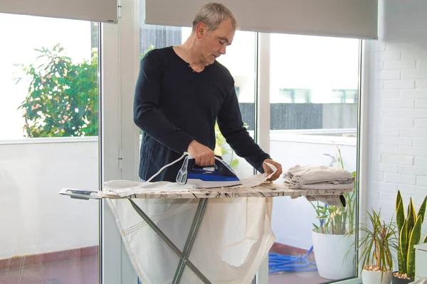 İnsan evde demirle ütü yapıyor, ev işlerinde eşitlik kavramı.