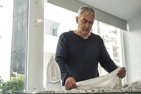 İnsan evde demirle ütü yapıyor, ev işlerinde eşitlik kavramı.