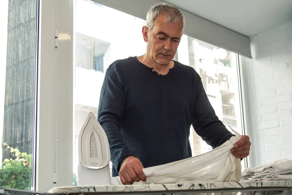 Evde ütüleyen olgun bir adam.