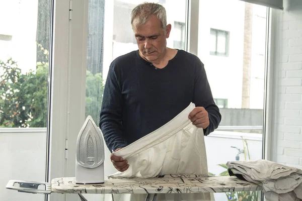 Evde ütüleyen olgun bir adam.