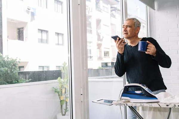 Olgun erkek gömlek evde ütü yaparken cep telefonunuzun konuşma