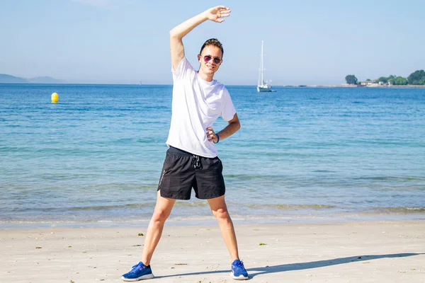 Genç adam plajda spor yapıyor.