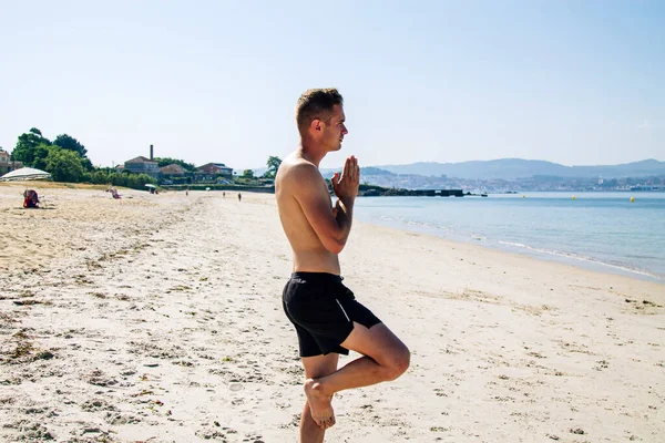 Genç adam plajda rahatlama, yoga ya da zen egzersizleri yapıyor.