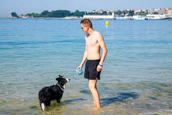 Sahilde evcil hayvanıyla oynayan bir adam.