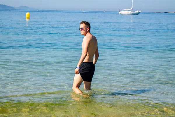 Kumsalda yıkanan yakışıklı genç adam.