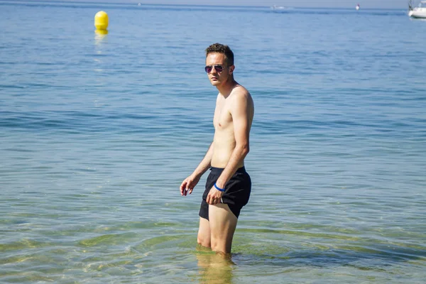 Kumsalda yıkanan yakışıklı genç adam.