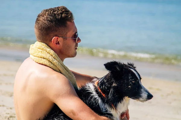 Plajda köpeğiyle genç bir adamın portresi.