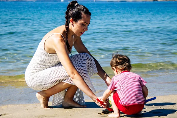 Anne kumsalda oğluyla kumdan kaleler yapıyor.
