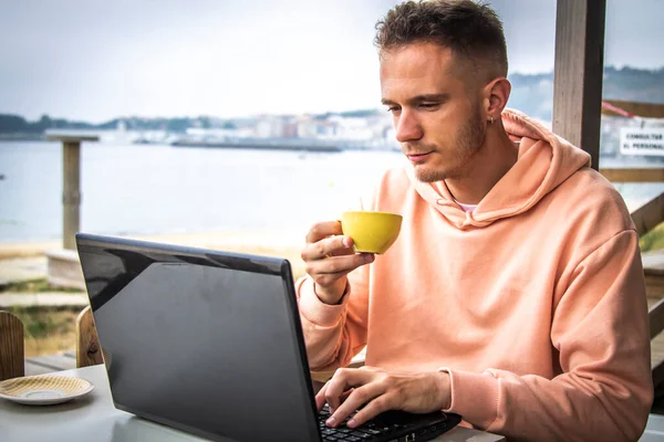 Bilgisayarlı genç adam kahve içiyor.