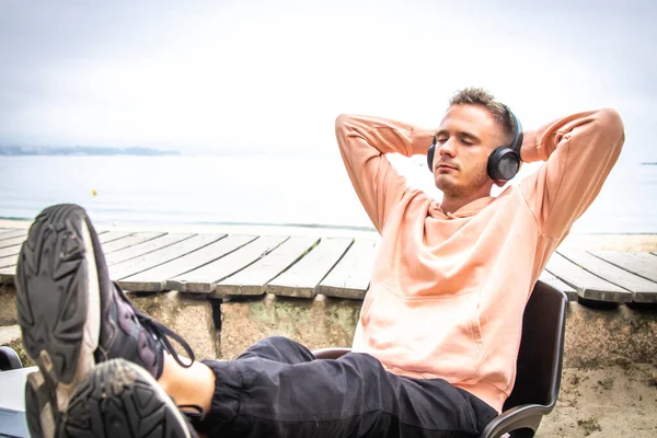 Kulaklıklı ve laptoplu rahat bir genç adam.