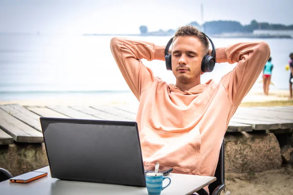 Kulaklıklı ve laptoplu rahat bir genç adam.