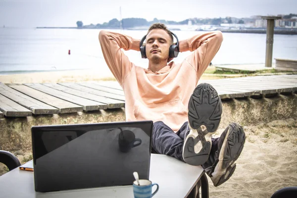 Kulaklıklı ve laptoplu rahat bir genç adam.