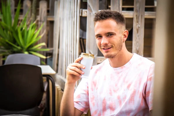 Genç adam terasta kahve içiyor.