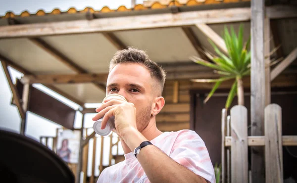 Genç adam terasta kahve içiyor.