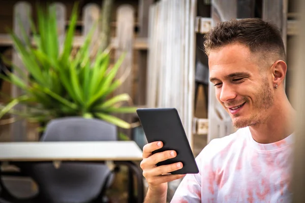 Açık kafede dijital tabletli ya da kitaplı bir adam