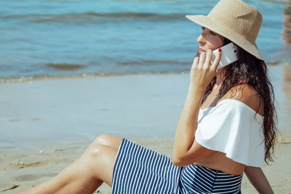 Женщина Шляпе Разговаривает Мобильным Телефоном Сидя Пляже — стоковое фото