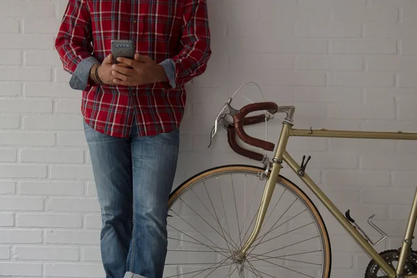 Evdeki adam bisikletin yanındaki duvara yaslanmış cep telefonuyla fotokopi çekiyor.