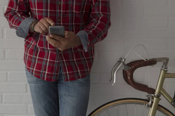 Evdeki adam bisikletin yanındaki duvara yaslanmış cep telefonuyla fotokopi çekiyor.