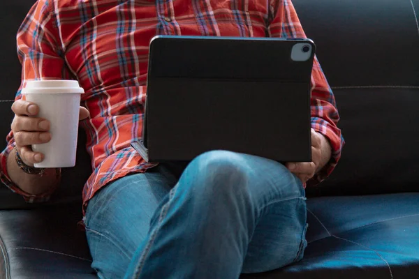 Dijital tabletli ve kanepede oturan hippi adam.