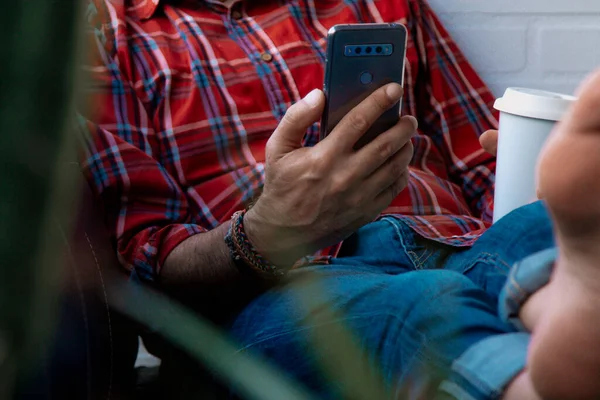 Kanepede uzanmış cep telefonu ve kahve olan hippi adam.