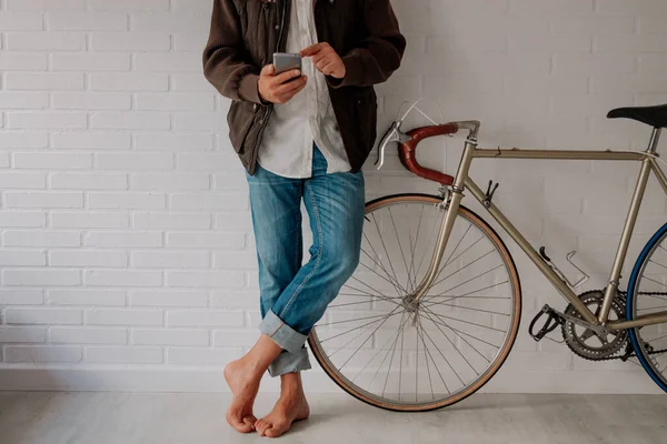 Cep telefonu ve bisikleti olan rahat bir adam.