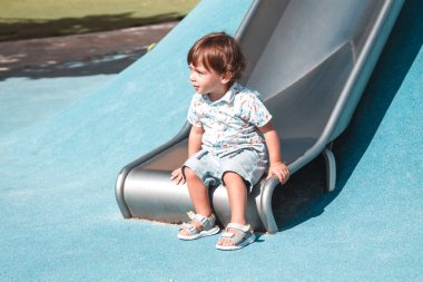Parktaki küçük çocuk kaydırağın keyfini çıkarıyor.